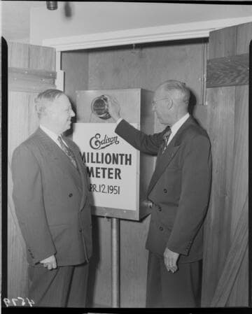 Two Edison executives standing next to installed "One Millionth Meter"