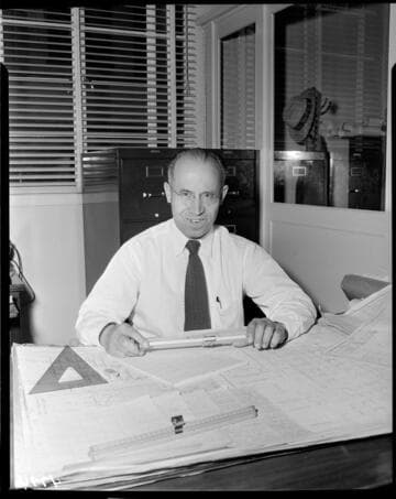 Engineer sitting at his desk with plans laid out
