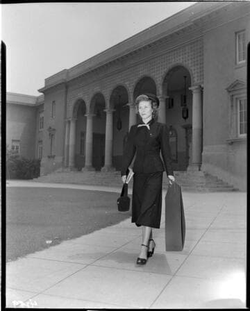 Lady appliance demonstrator with package walking from a stately building