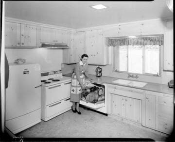 Woman loading dishwasher in electric kitchen