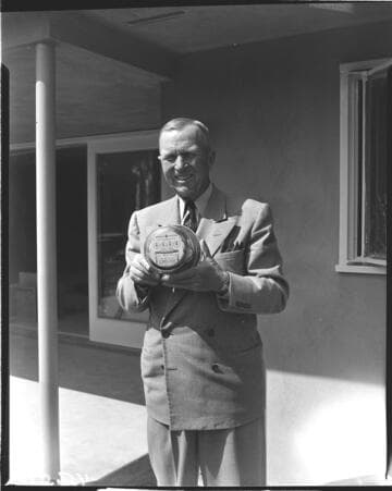 Man in suit holding the "One Millionth Meter" at the job site