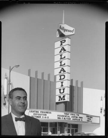 Man standing in front of the Hollywood Palladium with a Lighting Progress Exposition on the marquis