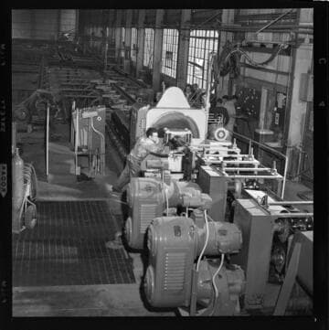 Large shafts or pipes being turned in a machine shop