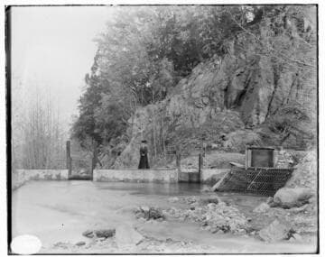 The intake for Mill Creek #3 Hydro Plant, a lady in a dress standing on the diversion dam