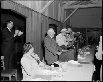 People standing and applauding a speaker at a banquet