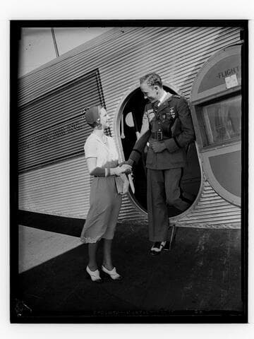 Military officer shakes hands with a woman as he exits an airplane