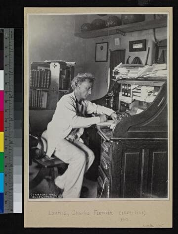 Charles F. Lummis sitting at his desk, writing