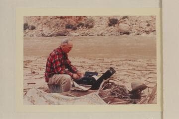 Randall Henderson typing up his notes during his traverse of the Grand Canyon in 1947, July