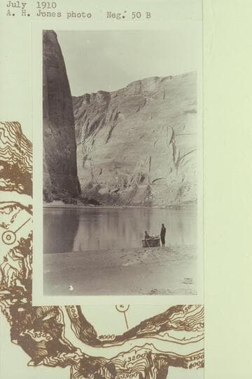 Skiff built at Lees Ferry in 1910, July, and on the beach a short distance up Glen Canyon.  Nungesser standing, McDermid seated.  Upstream view