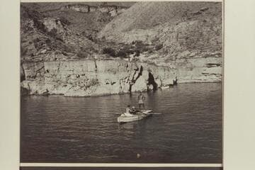 Last camp of the 1948 Nevills party on the ledge above  Lake Mead near Emory [sic] Falls. In the "Sandra" are Lucile Hiser; Garth Marston at the oars; and Masland standing on the stern