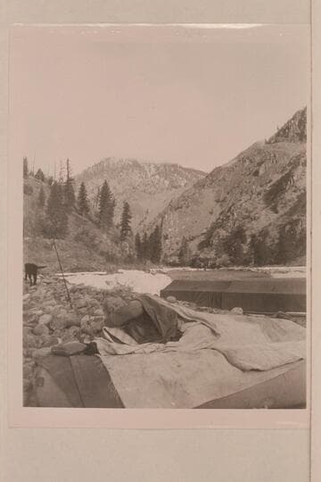 Carl Biedenbach in his bed on top of inflated boat.  Don Smith's 30-ft. sweep scow in background rigged with cover