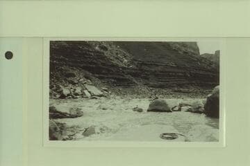 Emery Kolb pulling out into the eddy at the foot of Soap Creek Rapid after portage of the rapid on the right.  Leigh Lint views the operation from the rock.  Lees Ferry gauge:  22,700 cfs