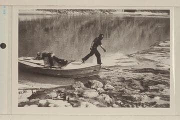Frank Dodge inspecting Holmstrom's boat as Buzz steps ashore; Diamond Creek