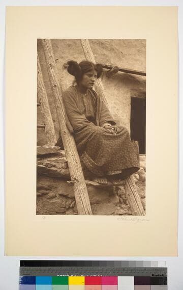 Hopi woman sitting on ladder at pueblo