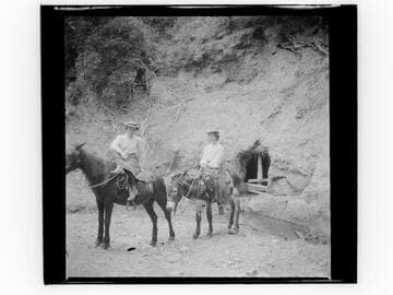 Two women riding burros in mountains