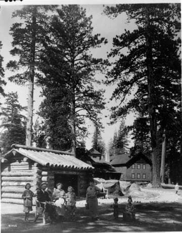 An unidentified family group sit in front of a rustic log structure known for many years as "Uncle Tom's Cabin."