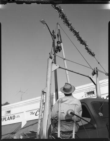 Utility workers hanging Christmas decorations on street light poles