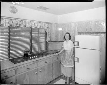 Lady standing in her kitchen by an electric range