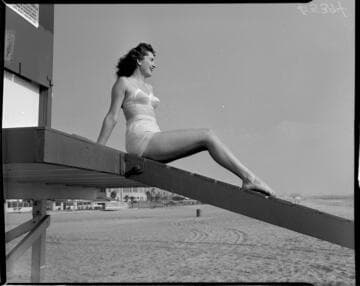 Woman in bathing suit sitting on lifeguard tower ramp at the beach