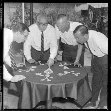 Men setting table with Reddy Kilowatts and "8 balls" on the table cloth