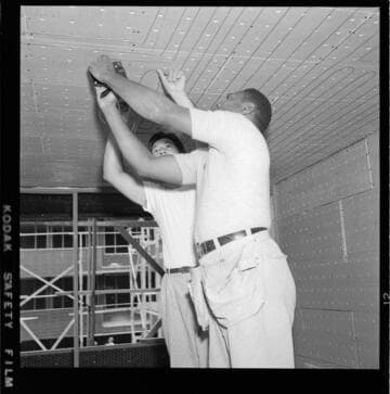 Men installing radiant heating conductors in ceiling during building construction