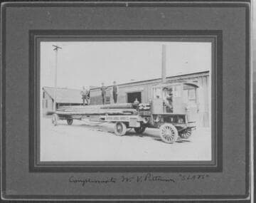 Southern Sierras Power Co. truck with load of poles in front of warehouse