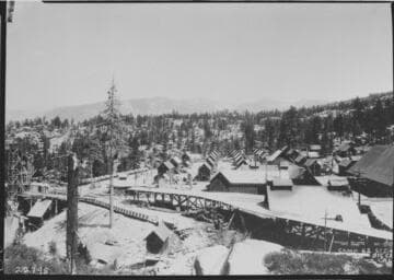 Establising shot of Camp 62 showing snowshed over tunnel tracks in foreground and concrete aggregate crushing and screening plant at extreme left