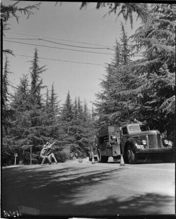 Men pulling wire wrapping machine along transmission line