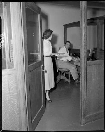 Woman leaving office with man seated at desk