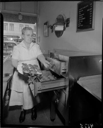 Lady with tray of muffins going into food warmer drawer
