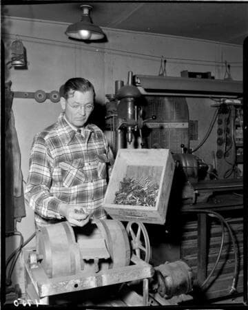 Man appears to be placing shell caseings in tumbler for polishing