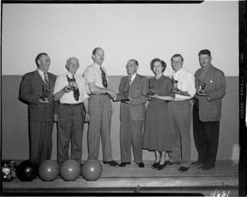 Five men and a woman receiving bowling trophys