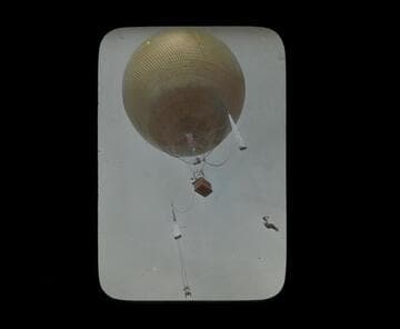 Balloon aloft with two men dangling from parachutes