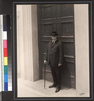 Portrait of Henry E. Huntington in front of bronze doors, approximately 1922